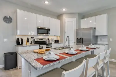 a kitchen with white cabinets and a large kitchen island with chairs at Last Minute Disney Getaway Private Pool Themed Bedrooms. Book Now 81913 in Orlando