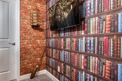 a book shelf filled with books next to a brick wall at Last Minute Disney Getaway Private Pool Themed Bedrooms. Book Now 87413 in Orlando