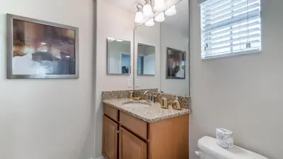 a bathroom with a sink and a toilet and a mirror at Last Minute Disney Getaway! Private Pool, Hot Tub & Games Room. Book Now! #56201 in Kissimmee