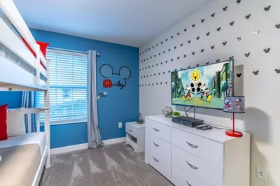 a bedroom with blue walls and a tv on a white dresser at Storey Lake Resort 1020 - Hosted by Top Villas in Kissimmee
