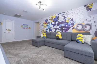a living room with a gray couch and a wall with minions at Last Minute Disney Private Pool Hot Tub Themed Bedrooms. Book Now 93745 in Kissimmee