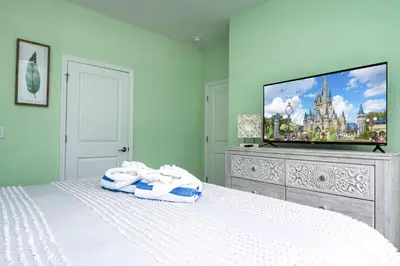 a bedroom with a white bed with a flat screen tv at Storey Lake Resort 1082 - Hosted by Top Villas in Kissimmee