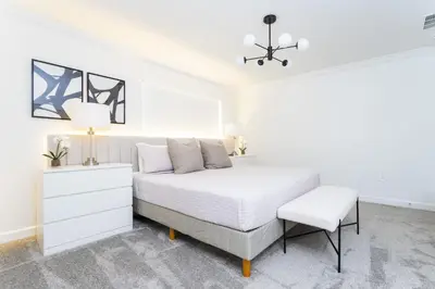 a white bedroom with a bed and a chair at Storey Lake Resort 1084 - Hosted by Top Villas in Kissimmee