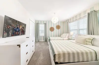 a white bedroom with two beds and a tv at Storey Lake Resort 1113 - Hosted by Top Villas in Kissimmee