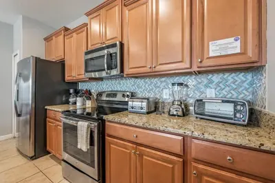 a kitchen with wooden cabinets and stainless steel appliances at Last Minute Disney Getaway Townhouse with Private Pool. Book Now 17222 in Kissimmee