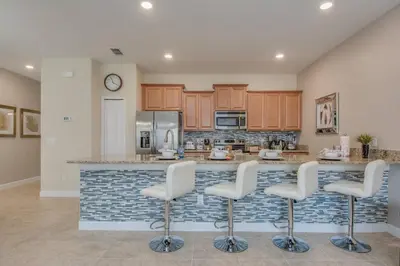 a kitchen with a bar with white stools at Last Minute Disney Getaway Townhouse with Private Pool. Book Now 17402 in Kissimmee