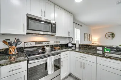 a kitchen with white cabinets and a stove top oven at Modern Florida Bungalow 3 Miles to Winter Garden! in Montverde