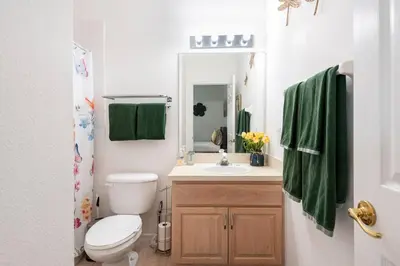 a bathroom with a toilet and a sink with green towels at Comfortable House with hot tub close to Disney in Kissimmee