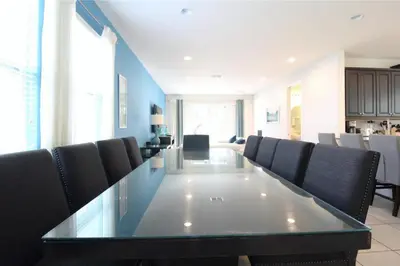 a dining room with a long glass table and chairs at Family Themed House Close to Disney with Private Pool and Huge Backyard in Orlando