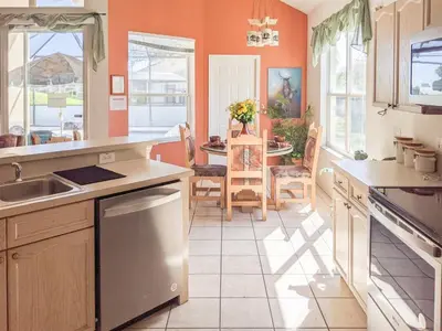 a kitchen with orange walls and a table and chairs at 5 Bed 8002 in Kissimmee