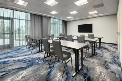a conference room with tables and chairs and a screen at Fairfield by Marriott Inn & Suites Orlando at Millenia in Orlando