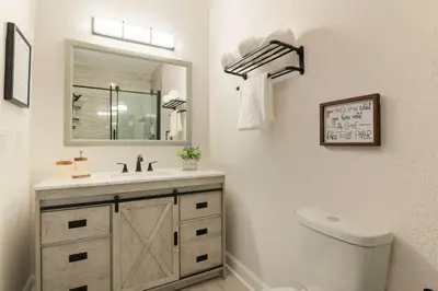 a bathroom with a sink and a mirror and a toilet at Newly Renovated First Floor 3Bed & 2 Bath, OUTDOOR POOL, 10-min to Disneyworld & Animal Kingdom! in Kissimmee