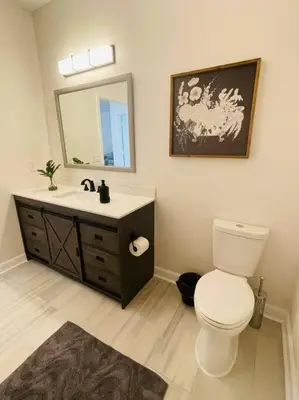 a bathroom with a toilet and a sink and a mirror at Newly Renovated First Floor 3Bed & 2 Bath, OUTDOOR POOL, 10-min to Disneyworld & Animal Kingdom! in Kissimmee