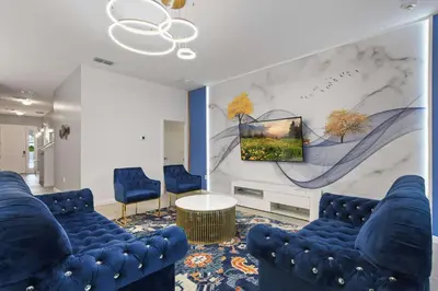 a lobby with blue chairs and a wall with a painting at Family-Friendly Luxury Home Near Disney & More in Kissimmee