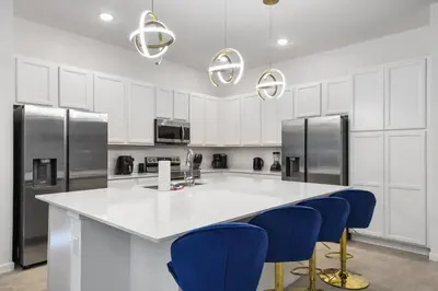 a kitchen with a white counter and blue chairs at Family-Friendly Luxury Home Near Disney & More in Kissimmee