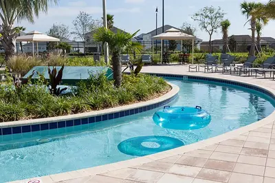 a blue swimming pool with chairs and tables in a resort at Luxurious 10-Bed Lakefront Retreat Near Disney in Kissimmee