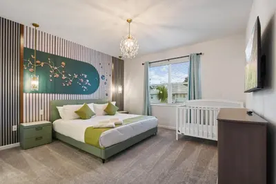 a bedroom with a bed and a crib in it at NEW Disney Themed 12BR Home Pool/SPA/Game/Tiki Bar in Kissimmee