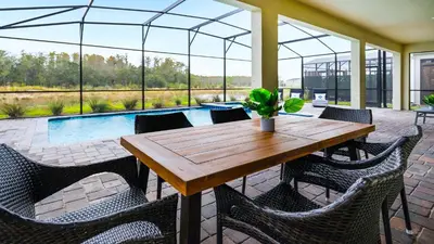 a patio with a wooden table and chairs and a pool at Elegant Retreat with Private Spa & Pool in Kissimmee