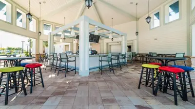 a covered patio with tables and chairs and a bar at Storey Lake Resort 6br Family Villa Pool by Disney in Kissimmee