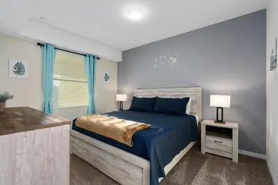 a bedroom with a bed with blue sheets and a window at Storey Lake 2BR Cozy Resort Home Close to Disney in Kissimmee