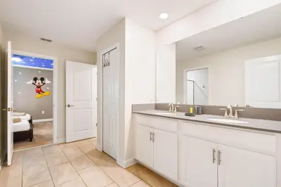 a kitchen with white cabinets and a sink and a room at Storey Lake Getaway Pool SPA Theater in Kissimmee