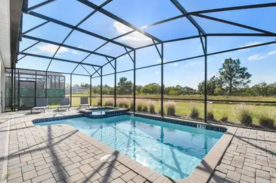 an indoor swimming pool in a glass house with a patio at Resort Home: Game Room, Pool, Near Disney in Kissimmee