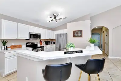 a kitchen with white cabinets and black chairs at Lakeview Luxury Oasis in Kissimmee