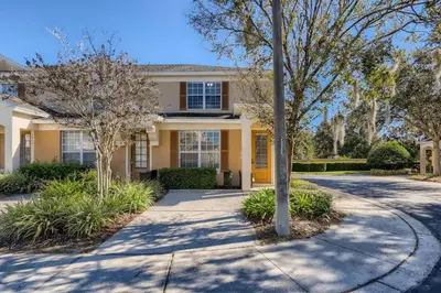 a yellow house with trees in front of a driveway at T2501M Windsor Hills Resort 3Bedrm Private Pool in Orlando