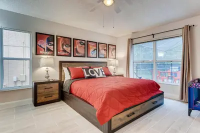 a bedroom with a red bed and some windows at H8438S Emerald Island Resort One Level POOL Pet OK in Kissimmee