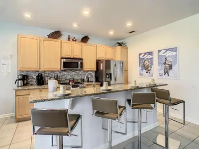 a kitchen with a large counter with stools at H2713M Windsor Hills Resort 4Bedrm POOL SPA Disney in Orlando