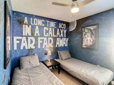 a room with two beds and a wall with a long the koived in at H8536 Single Level Pool Spa Home 5 Bed Near Disney in Kissimmee