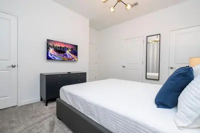 a white bedroom with a large bed with blue pillows at Charming 4Bd w Private Pool @ Storey Lake Resort 2653 in Kissimmee