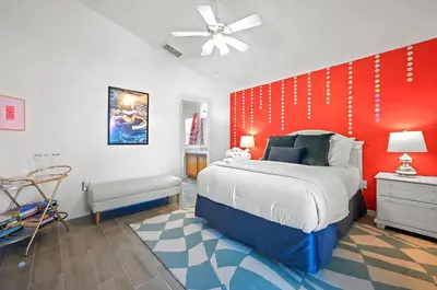 a bedroom with a bed and a red wall at Disney World Getaway: 4 Br - Sunroof - BBQ Bliss in Orlando