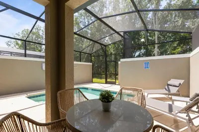 a patio with a table and chairs and a swimming pool at New Home 5 Bedrooms and 4 Bathrooms At Storey Lake in Kissimmee