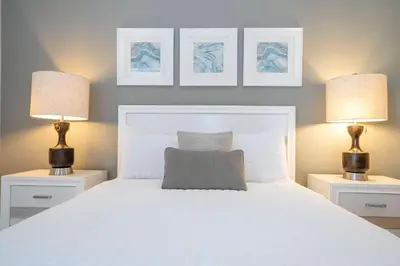 a bedroom with a white bed with two lamps at Awesome 4 Suites Villa 5 Min to Disney in Orlando