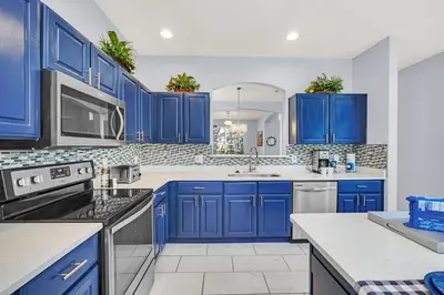 a blue kitchen with white counter tops and blue cabinets at 8462 Secret Key Cove in Kissimmee