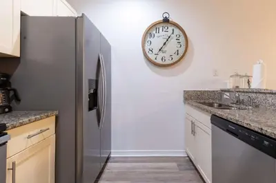 a kitchen with a refrigerator and a clock on the wall at Fabulous townhome near the Parks in Kissimmee