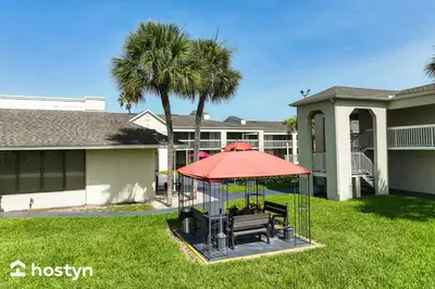 a gazebo with a bench and a red umbrella at Amazing hotel room near Disney for 4 people in Kissimmee