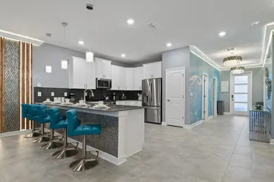 a kitchen with white cabinets and blue bar stools at 5 Star Exceptional Luxury Villa at Storey Lake mins to Disney in Kissimmee