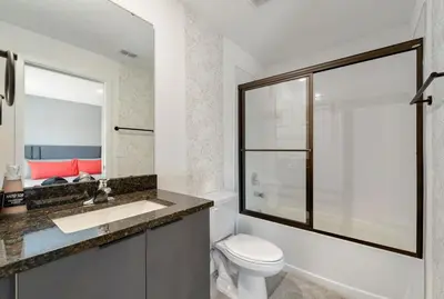 a bathroom with a toilet and a sink and a mirror at 3MI from Disney- Modern 3BD 3BA + Grill in Kissimmee