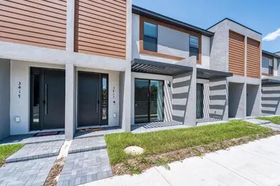 a modern house with glass doors and a sidewalk at 3MI from Disney- Modern 3BD 3BA + Grill in Kissimmee
