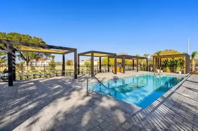 a large swimming pool with a pavilion next to it at 3MI from Disney- Modern 3BD 3BA + Grill in Kissimmee