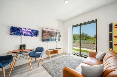 a living room with a couch and a table and chairs at 3MI from Disney- Modern 3BD 3BA + Grill in Kissimmee