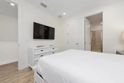 a white bedroom with a bed and a flat screen tv at Private Pool! Big and Stylish House! in Orlando