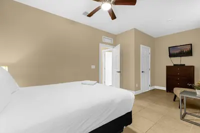 a bedroom with a white bed and a ceiling fan at Summer Stay - Renovated TownHome by Disney! in Orlando