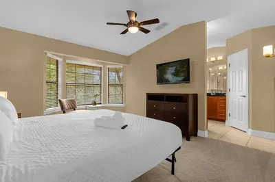 a bedroom with a white bed and a ceiling fan at Cozy & Elegant 4BR Enchanted Townhouse - 1 Mile to Disney with Resort Pool, Gym, & Jacuzzi in Orlando