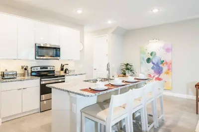 a kitchen with white cabinets and a table with white chairs at 8005 Stunning Villa Disney Park Proximity in Orlando