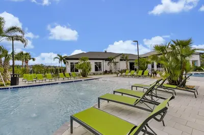 a swimming pool with green chairs and a building at Storey Lake Escape w/ Pool, Games & Water Park in Kissimmee