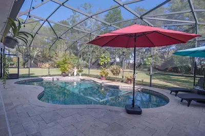 a red umbrella sitting next to a swimming pool at Paradise in a country setting 1100 sq ft apartment in Lake Mary