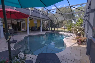 a swimming pool with an umbrella next to a building at Paradise in a country setting 1100 sq ft apartment in Lake Mary
